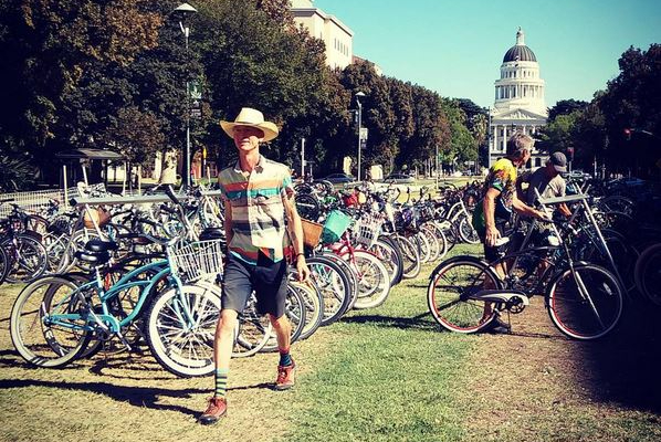 A man walks by a large group of parked bikes.