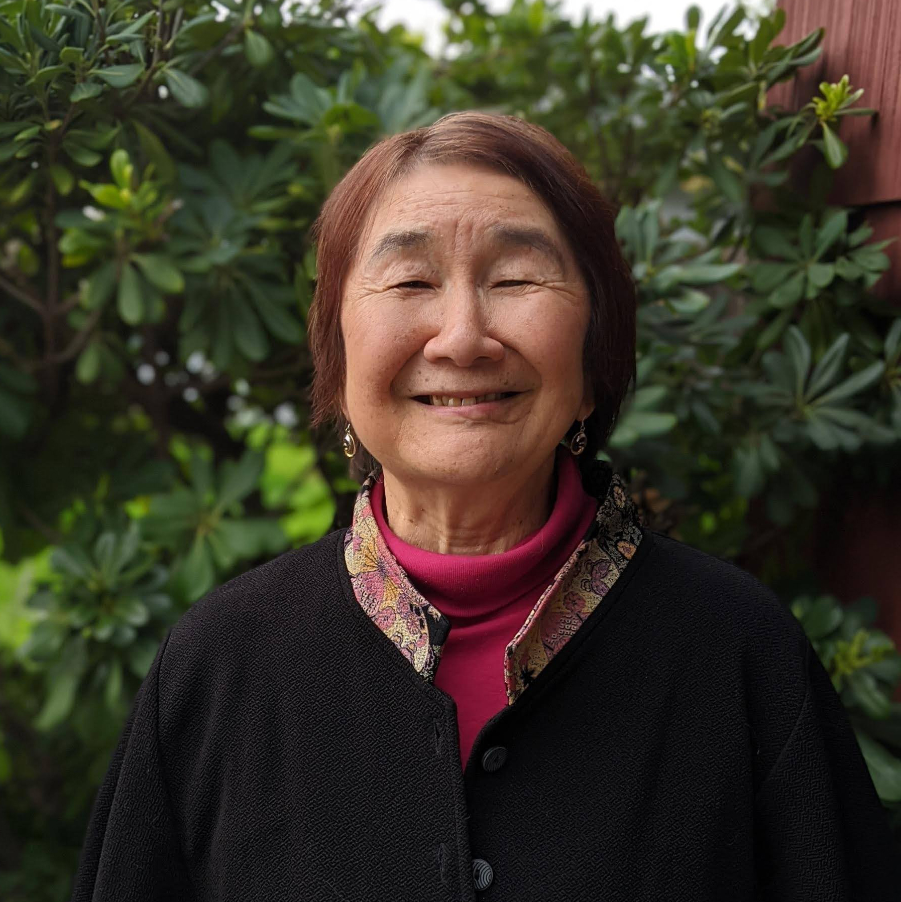 Headshot of an Asian woman with short dark hair and a red scarf.