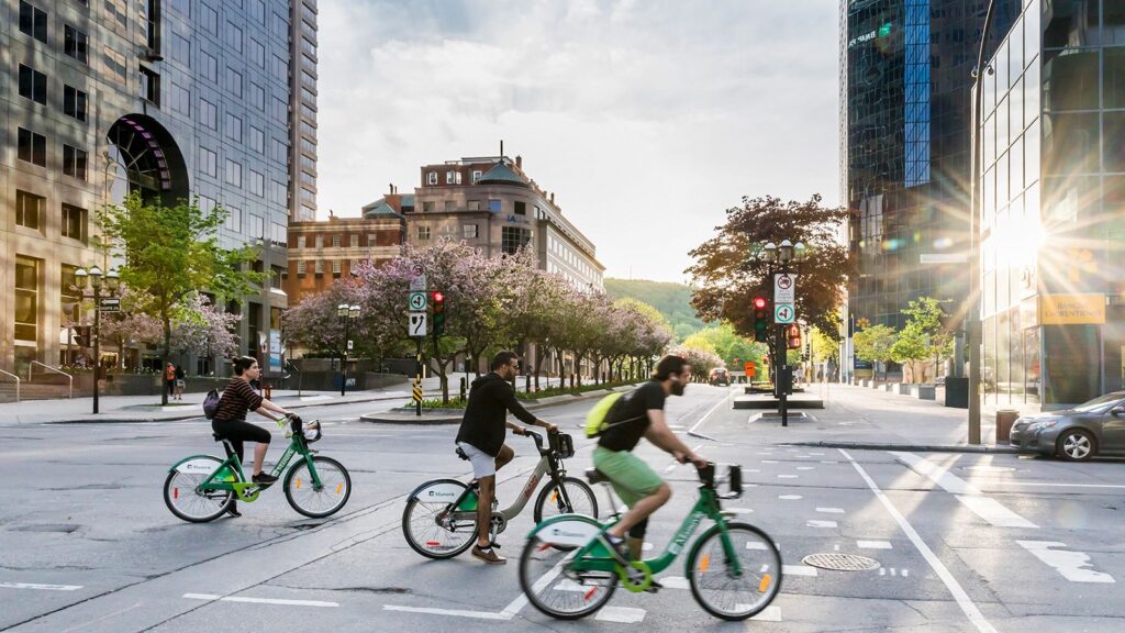 Three bicyclists ride through a city.