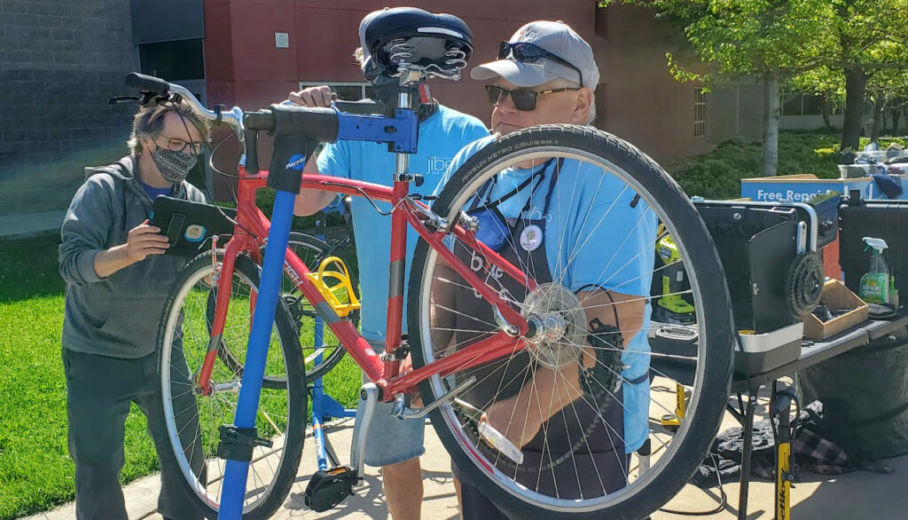 Three men work on a bike that's on a stand.