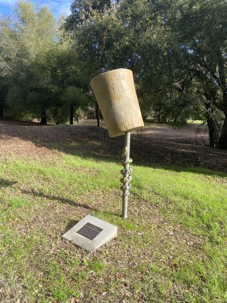 A large cork sits on top of a pole that has a snake wrapped around it.