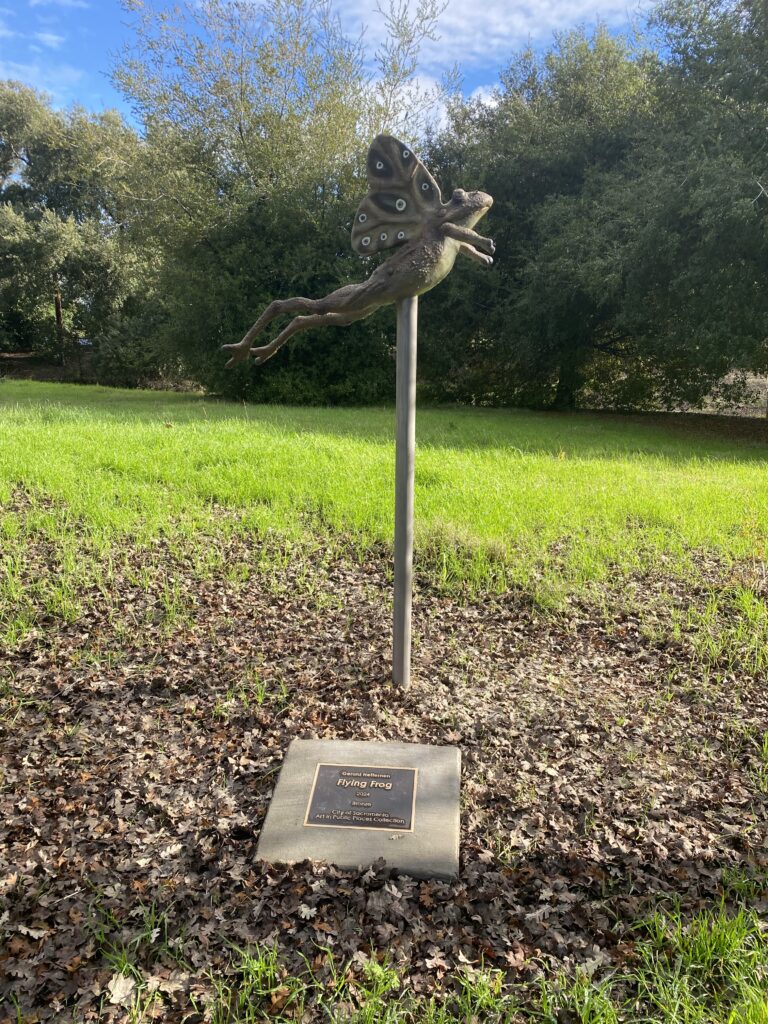 A flying frog on top of a post.