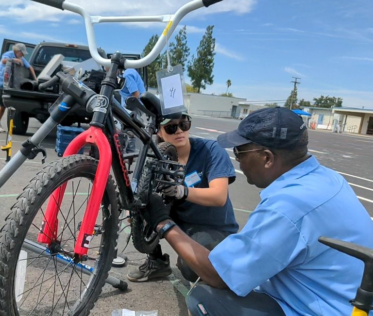 A man and a woman work on a bicycle.
