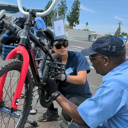 A woman and a man work on a bicycle.