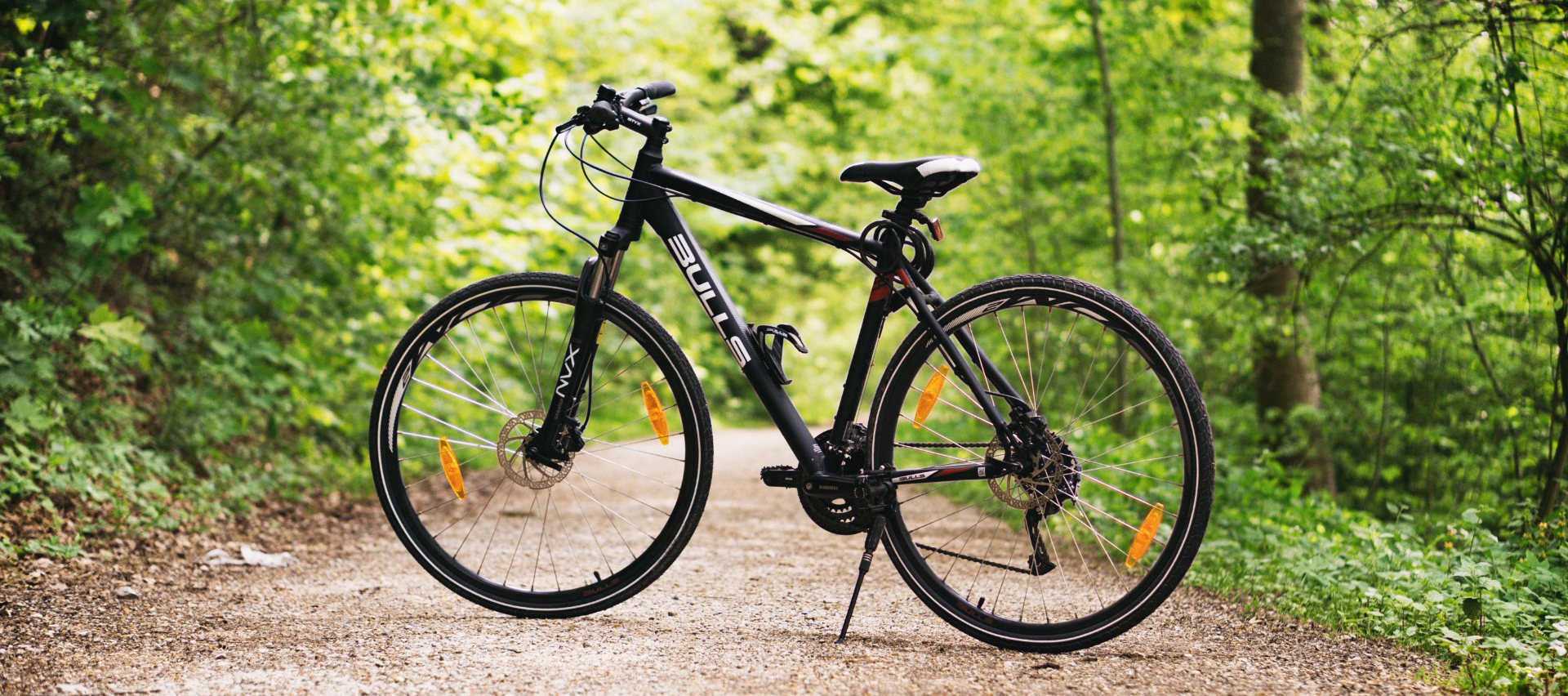 Black bike on a dirt trail in the woods.