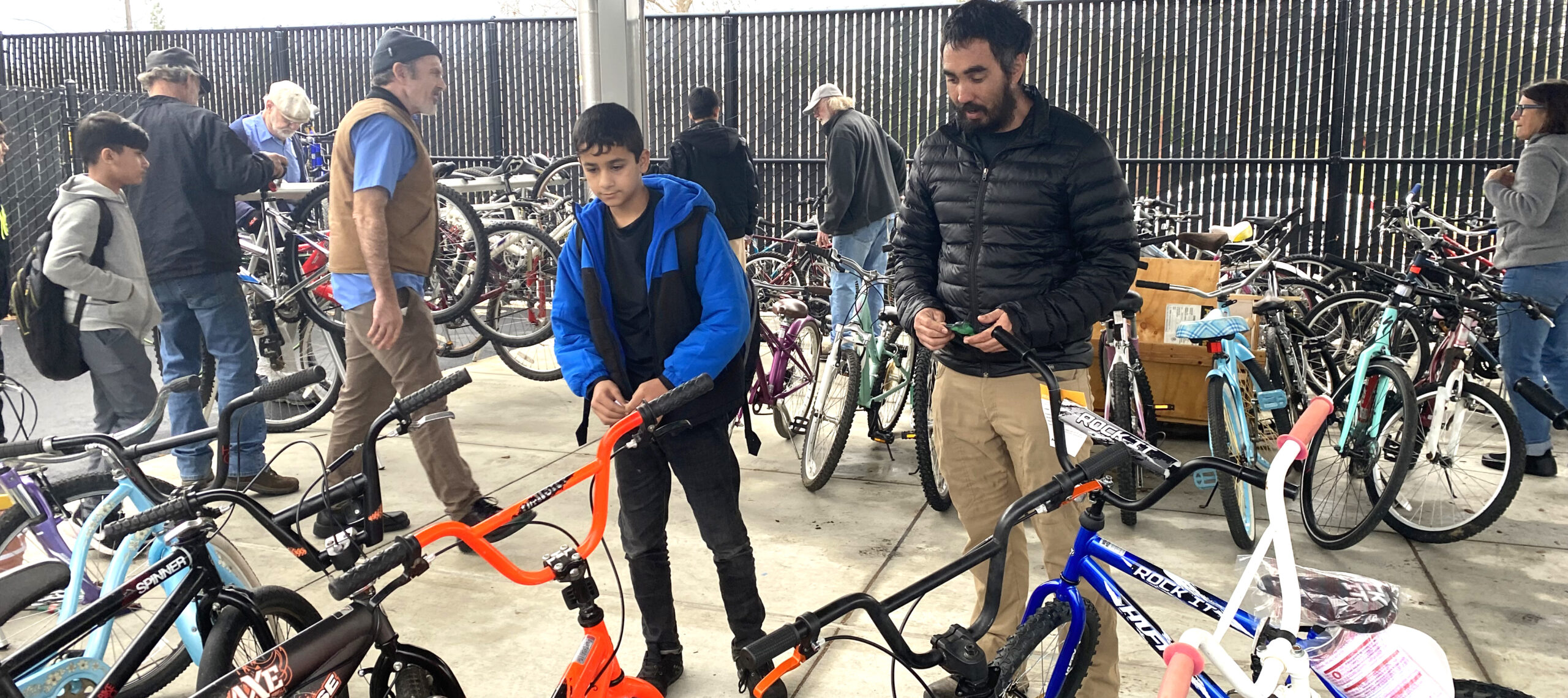 At a school, adults and children check out donated bikes.