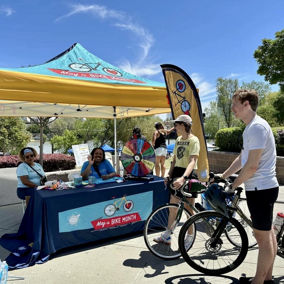 A cyclist stands outside a May is Bike Month booth.