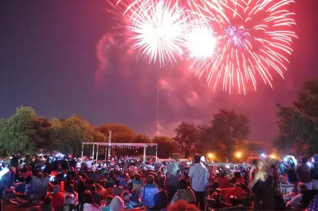 A large crowd of people watch fireworks.