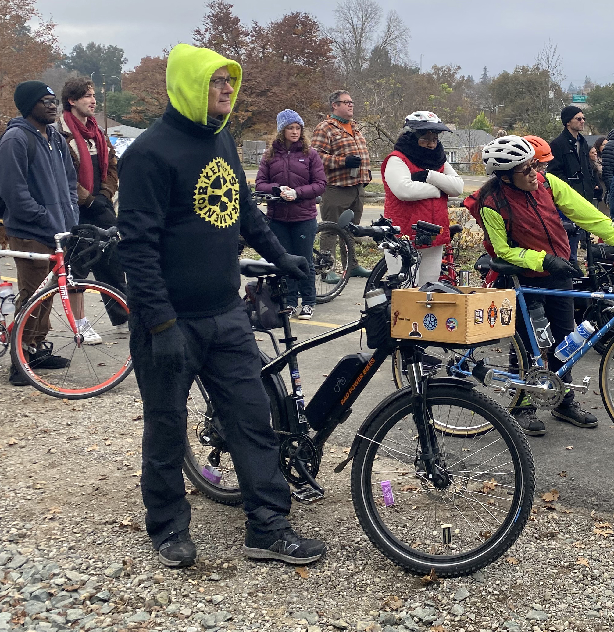 A group of people stand with their bikes on a dirt trail.